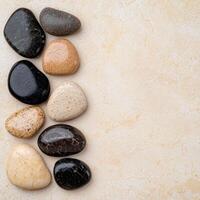 Assorted smooth river rocks on a light stone background photo