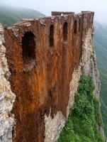 Rugged cliffside with natural rock formations and lush greenery photo