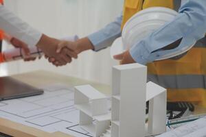 Construction and structure concept of Engineer or architect meeting for project working with partner and engineering tools on model building and blueprint in working site, contract for both companies. photo