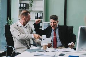 Two happy colleagues with laptop and documents in office photo
