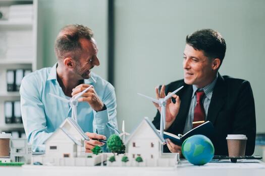 Engineers meeting about wind turbine model and house model. Renewable energy and housing development concept. Team of architects and engineers in modern office discussing design structure. photo