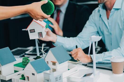 Engineers meeting about wind turbine model and house model. Renewable energy and housing development concept. Team of architects and engineers in modern office discussing design structure. photo