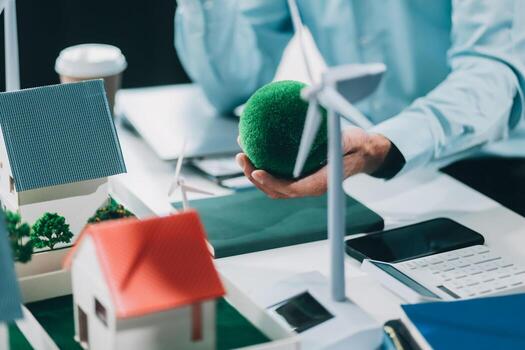 Engineers meeting about wind turbine model and house model. Renewable energy and housing development concept. Team of architects and engineers in modern office discussing design structure. photo