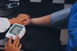 A doctor taking a patient's blood pressure. The patient's arm is equipped with a blood pressure cuff, and the doctor is using a blood pressure monitor. photo