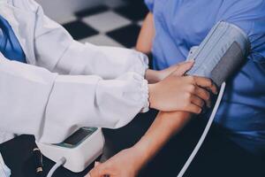 A doctor taking a patient's blood pressure. The patient's arm is equipped with a blood pressure cuff, and the doctor is using a blood pressure monitor. photo