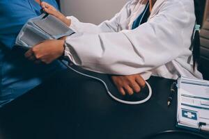 A doctor taking a patient's blood pressure. The patient's arm is equipped with a blood pressure cuff, and the doctor is using a blood pressure monitor. photo