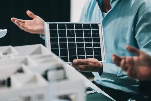 Engineers meeting about wind turbine model and house model. Renewable energy and housing development concept. Team of architects and engineers in modern office discussing design structure. photo