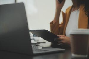 Close up Business woman using calculator and laptop for do math finance on wooden desk, tax, accounting, statistics and analytical research concept photo