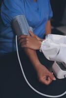 A doctor taking a patient's blood pressure. The patient's arm is equipped with a blood pressure cuff, and the doctor is using a blood pressure monitor. photo