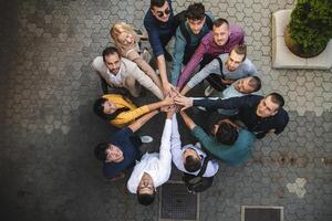 Top view photo of a group of business people and colleagues standing together holding hands, looking towards the camera, symbolizing unity and teamwork.