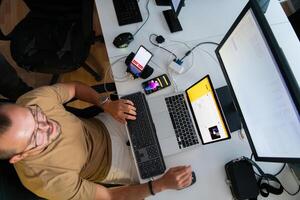 Top view of programmer diligently testing smartphone applications while sitting in their office. photo