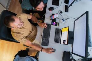 Top view of programmer diligently testing smartphone applications while sitting in their office. photo