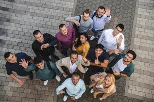 Top view photo of a group of business people and colleagues standing together holding hands, looking towards the camera, symbolizing unity and teamwork.