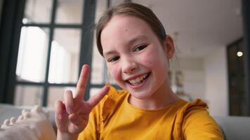 Playful Caucasian little girl child happy daughter making selfie photo on device smiling schoolgirl grimacing kid type screen display mobile phone at home point of view smartphone webcam photography video