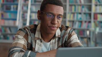 Bored African American man male guy tired fatigue overworked library high school university diploma challenge task homework student laptop e-learning desktop computer working deadline cyberspace web video