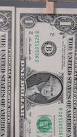 A close-up of a one-dollar bill shows George Washington's portrait, serial number, and Treasury seal in natural light, highlighting the bill's details and features. video