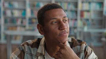 African American man male student library knowledge think contemplation new idea inspiration guy touching chin brainstorming imagination decisions high school university studying learning bookshelf video