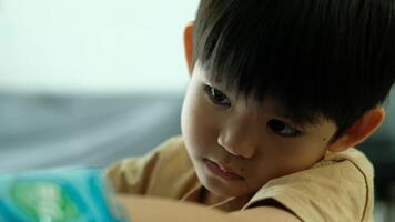 An Asian boy is watching something with interest while eating some snacks. video