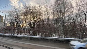 View from a moving vehicle. Clip. View of the road in springtime with melting snow and buildings with cars removed in motion. video