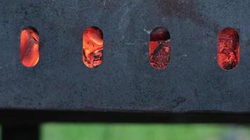 A small brazier filled with burning wood. Concept. Close up of red burning coals through the holes of chargrill. video