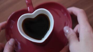 Close up top down view of woman hands taking small cup and plate of coffee from the table. Concept. Red crockery in a form of cute heart. video
