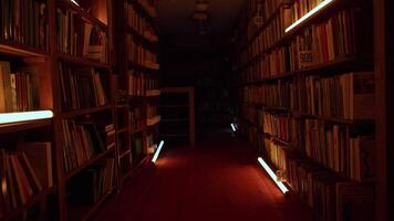 The dark library. Stock footage. A room with large cabinets where there are books and magazines and playing lights in the dark. video