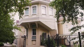 View of beautiful white house with green trees. Stock footage. Facade of old European-style house with green courtyard. Architecture of beautiful white house for old residential area in summer video