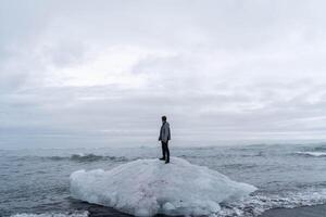Man Standing on a Floating Iceberg in the Ocean photo
