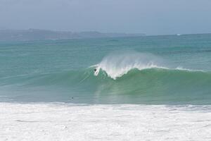Surfer taking off in a big A-frame wave at VVF, Anse l'etang, tartane, Martinique, West Indies, France photo