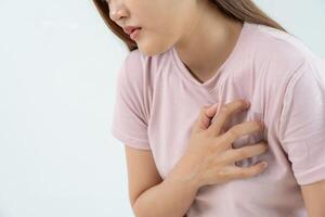 hand hold chest with heart attack symptoms, asian woman have chest pain caused by heart disease, leak, dilatation, enlarged coronary heart, press on the chest with a painful expression photo