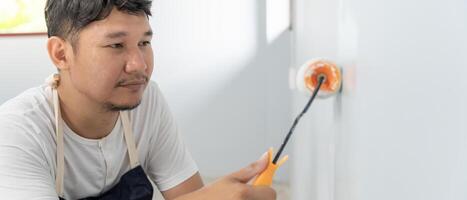 painter man, brush in hand for products to restore and paint the wall, indoor the building site of a house, wall during painting, renovation, painting, contractor, Architect, construction worker photo