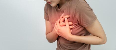 hand hold chest with heart attack symptoms, asian woman have chest pain caused by heart disease, leak, dilatation, enlarged coronary heart, press on the chest with a painful expression photo