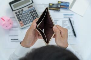 Stressed and headache man with large bills or invoices no money to pay to expenses and credit card debt. shortage, Financial problem, bankruptcy, mortgage, loan, bankrupt, poor, empty wallet photo