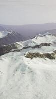 large snow patch left over on the volcanic rock field of a mountain in summer video