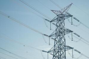A High Voltage Power Line Tower Stands Majestically Tall Against a Pristine Clear Blue Sky Above photo