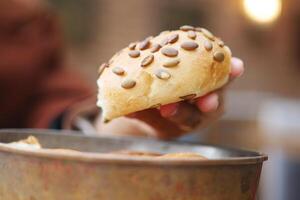 un mano sostiene un sembrado un pan rodar encima un cuenco de Fresco ingredientes para comida deberes foto