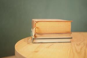 A Beautiful Arrangement of Stacked Books on a Wooden Table Set Against a Subtle Green Background photo