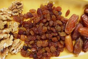 A colorful assortment of Mixed Nuts and Dried Fruits elegantly arranged on a vibrant Yellow Plate photo