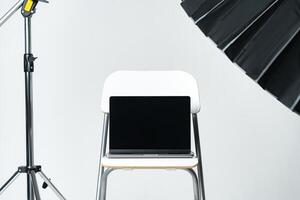 Laptop with black screen and photography equipment in photostudio photo