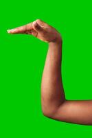 A hand making a gesture with a green background during daylight photo