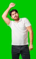 A young man in a white polo shirt dances energetically against a vibrant green background photo