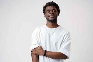 Portrait of a smiling young african man wearing white t-shirt standing over gray background photo