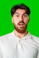 Surprised young man with a beard expressing shock against a bright green background photo