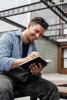 A person writes in a notebook while sitting on a park bench photo