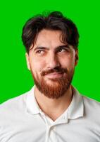 A smiling young man with a beard poses against a bright green background photo