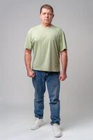Man in casual attire standing posed against a neutral background, displaying a serious expression photo