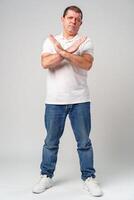 A man making a gesture of refusal with arms crossed against a light background photo