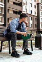 A person writes in a notebook while sitting on a park bench photo