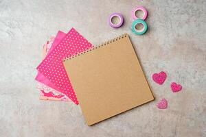 Creative supplies for scrapbooking and crafting on a textured surface with decorative tape and heart confetti photo
