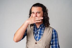 Man making a funny face while pinching his nose in a studio setting with a neutral background photo